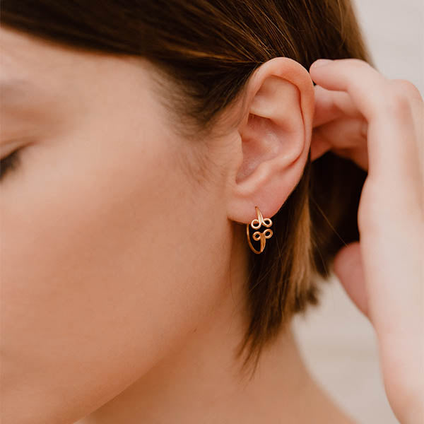 ragazza indossa piccoli orecchini cerchio oro giallo ghirigori fatti a mano italia