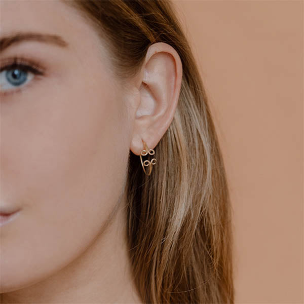 ragazza indossa piccoli orecchini cerchio oro giallo ghirigori fatti a mano italia