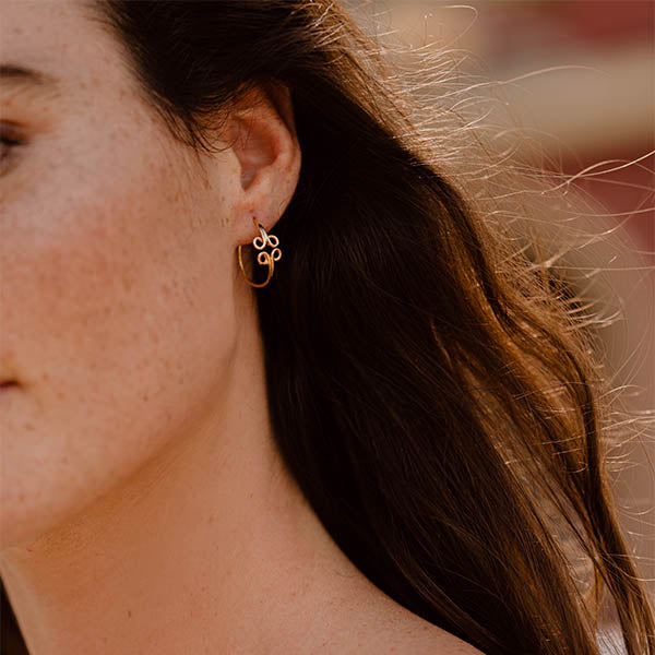 ragazza indossa piccoli orecchini cerchio oro giallo ghirigori fatti a mano italia