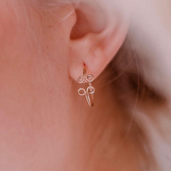 ragazza indossa piccoli orecchini cerchio oro rosa ghirigori fatti a mano italia