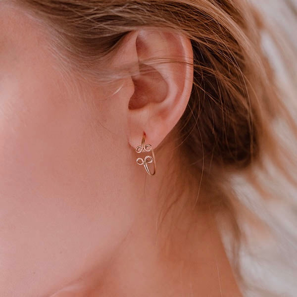 ragazza indossa piccoli orecchini cerchio oro rosa ghirigori fatti a mano italia